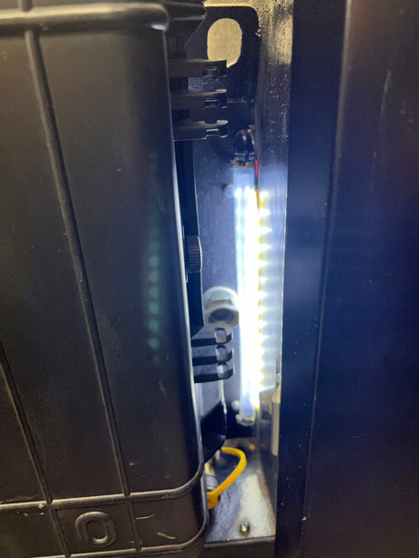 Inside an RV rental, bright LED strip lights illuminate a dark internal compartment, showcasing RV systems.