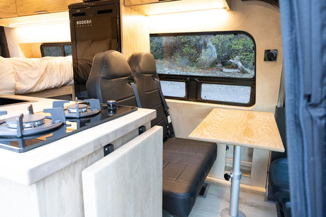Explore this RV rental's spacious camper van interior with a kitchen, comfy bed, seating, and scenic views.
