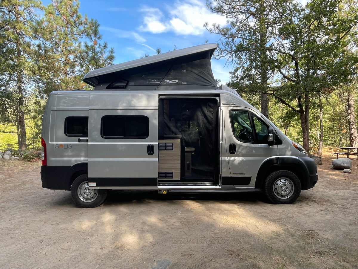 Silver Winnebago Solis pop-top **RV rental** parked outdoors with the side door open
