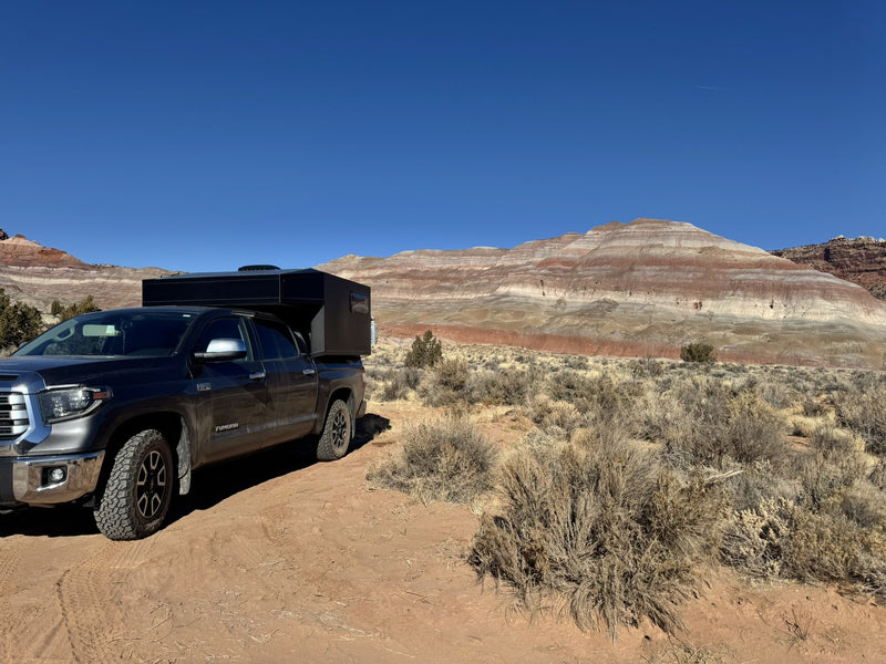The Moonlander X camper and Tundra parked on red dirt in front of banded desert hills — photo 9
