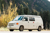 White VW camper van, perfect for an rv rental, parked amidst vibrant yellow fall foliage and mountain scenery.