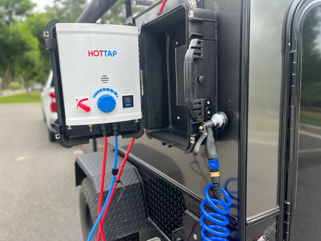 A HOTTAP portable hot water heater & shower unit, mounted on an RV rental trailer, for outdoor hot showers.