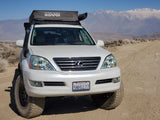 White Lexus SUV modified for overlanding with an iKamper rooftop tent on a dirt trail, a rugged RV rental alternative.