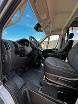Inside an **RV rental** cab. Shows the spacious driver's area, passenger seat, and clear outdoor view through the windshield.
