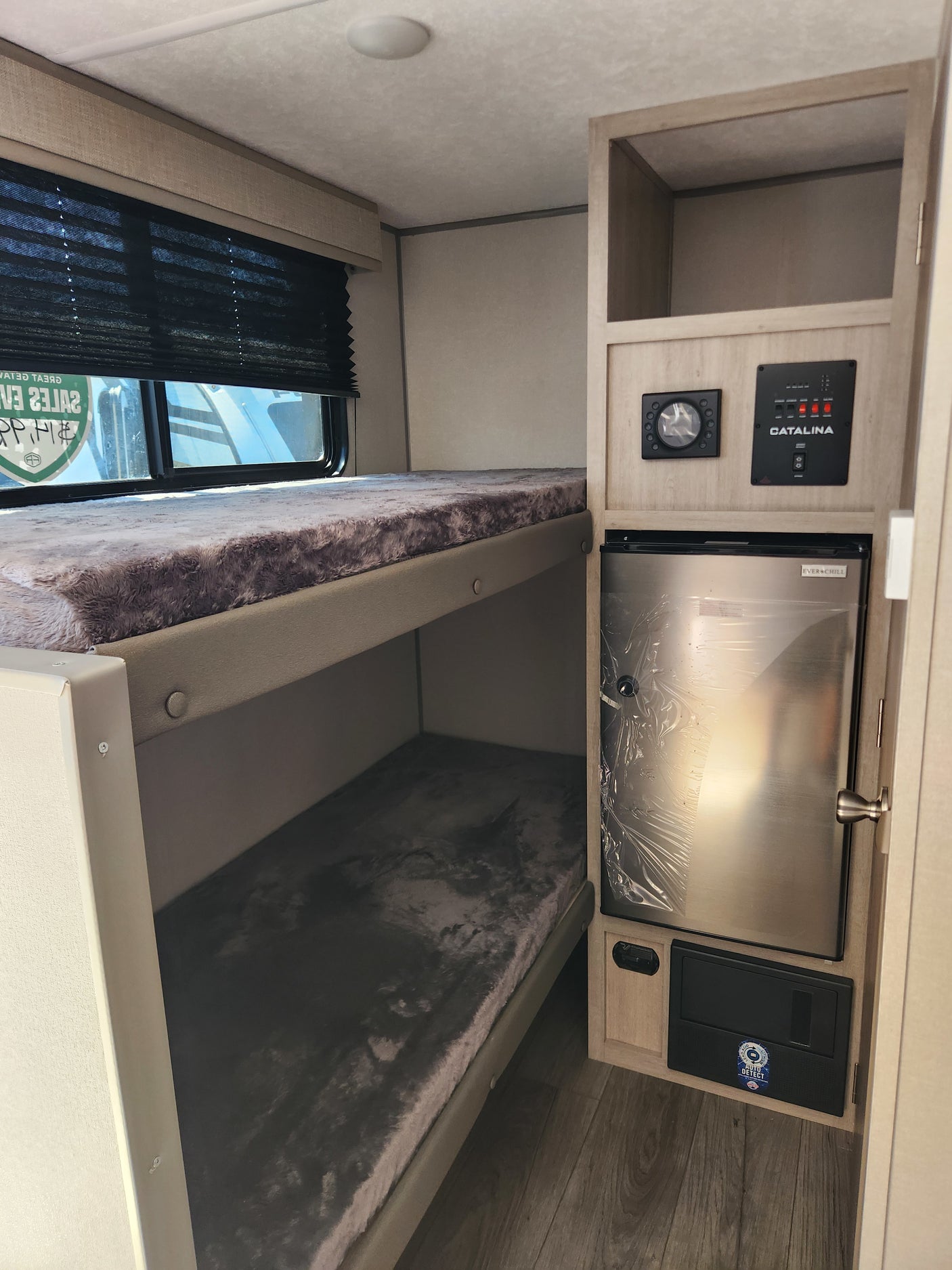 An RV rental interior with cozy bunk beds, an Ever Chill compact fridge, and Catalina controls. Ready for adventure.
