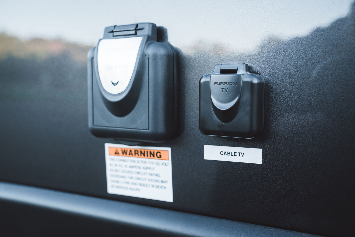 RV rental exterior panel: Furrion 20A electrical and cable TV hookups, with safety warning label below.