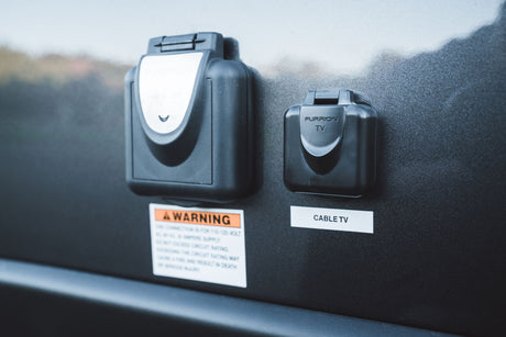 RV rental exterior panel: Furrion 20A electrical and cable TV hookups, with safety warning label below.