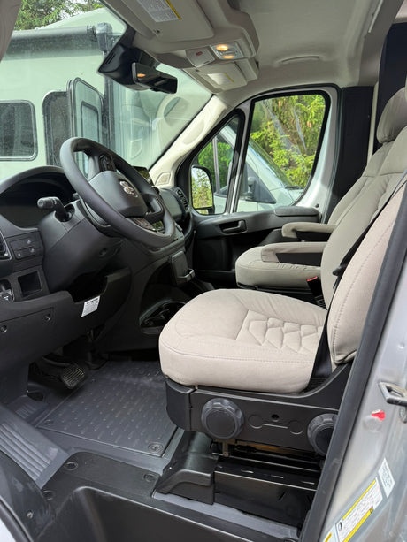**RV rental** driver's cabin: Steering wheel, dashboard, and light beige seats ready for the road.