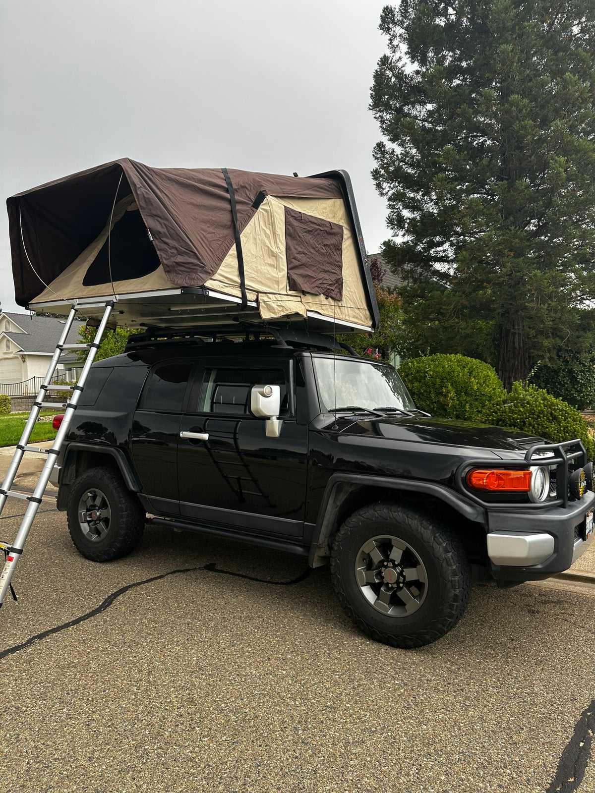 Black FJ Cruiser with a brown rooftop tent deployed, ladder extended. Perfect for an adventure rv rental. — photo 3