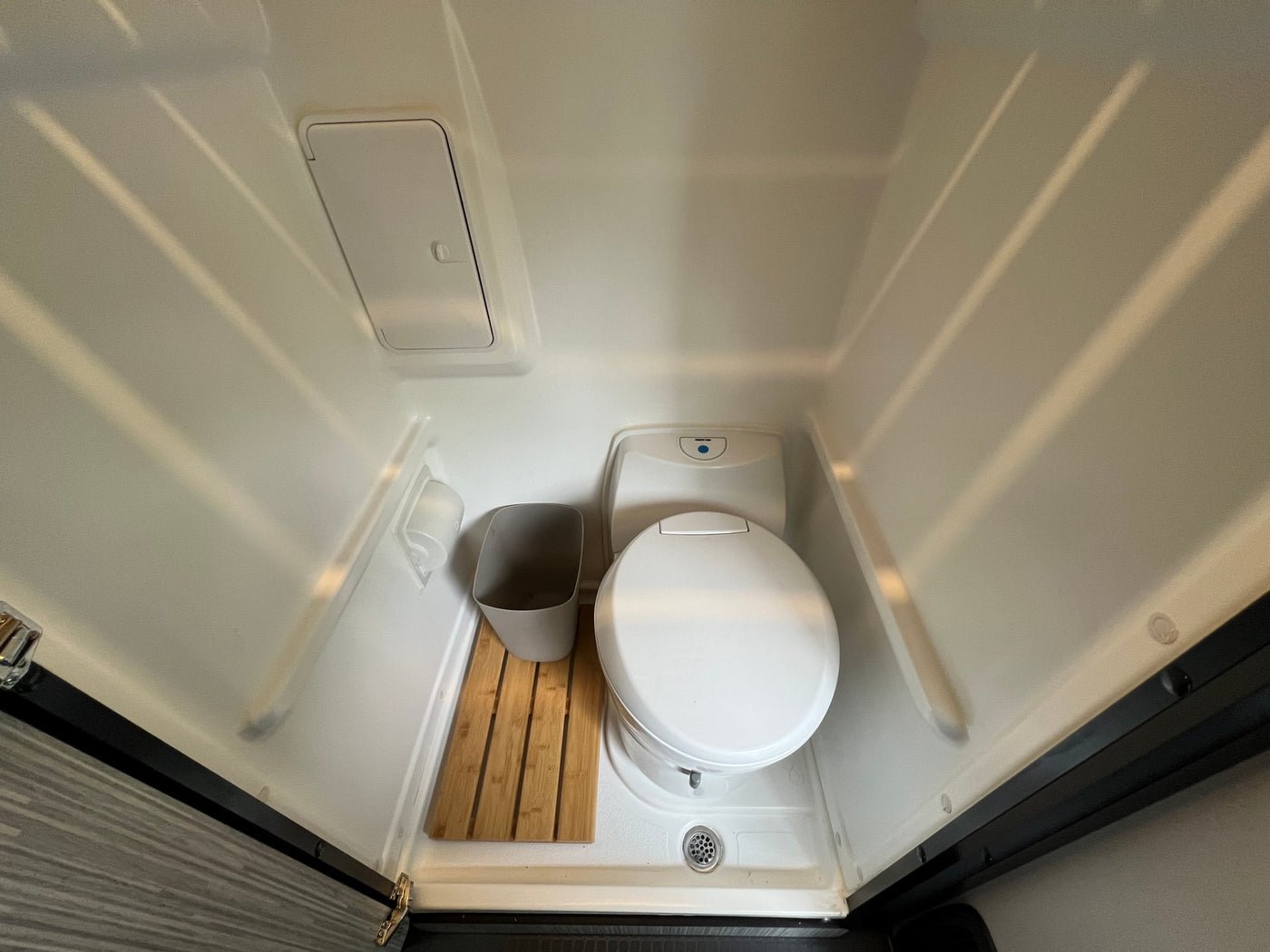 Compact RV rental wet bath with toilet, wooden floor mat, and drain for practical use. — photo 10