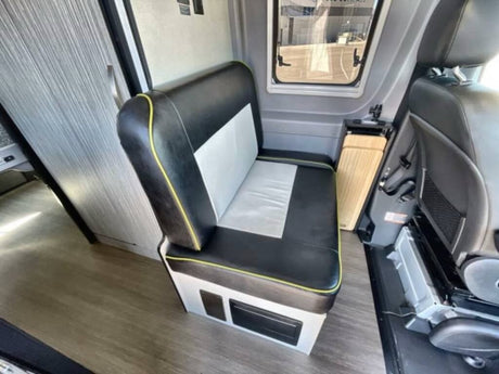 Explore this RV rental interior, featuring a two-tone bench seat with yellow trim, wood flooring, and a side window.