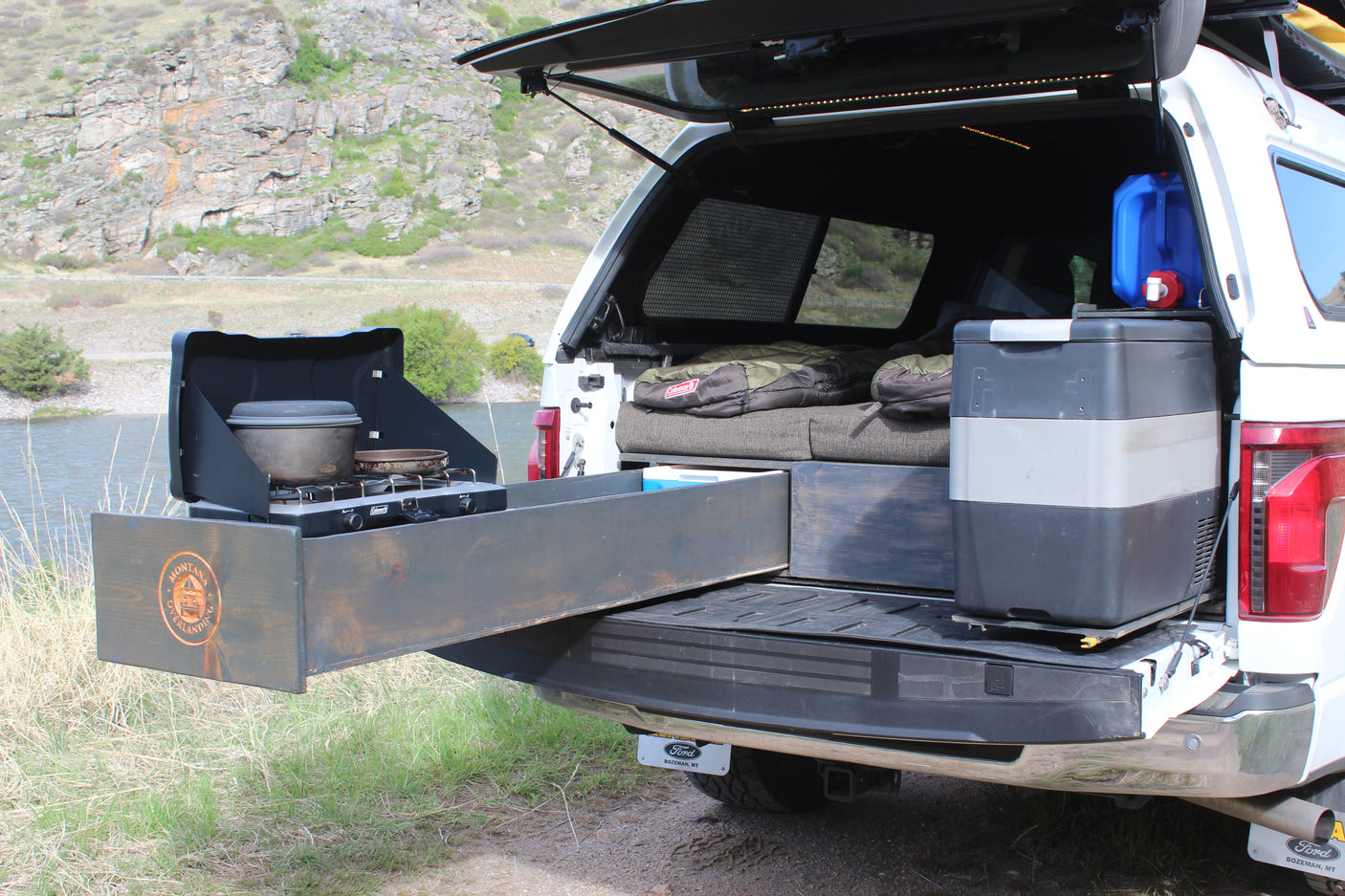 Explore with an RV rental! This truck bed camper boasts a pull-out kitchen, fridge, water, and sleeping bags for rugged adventure.