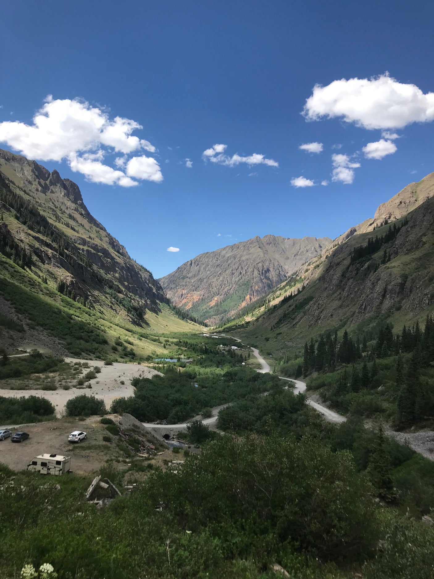 Scenic mountain valley, winding road, and parked RVs under blue skies. Ideal for your next rv rental adventure!