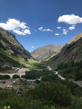 Scenic mountain valley, winding road, and parked RVs under blue skies. Ideal for your next rv rental adventure!