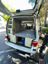 Inside a white camper van: a cozy bed, ample storage, and functional features, ready for your next RV rental trip.