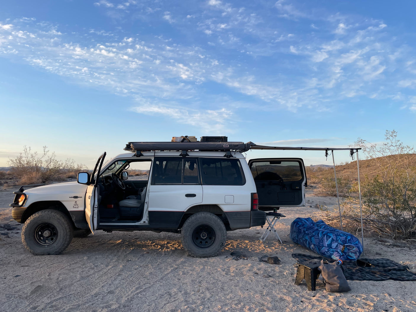 Overlanding SUV with awning set up in the desert for camping, a great alternative to an RV rental for off-grid trips.