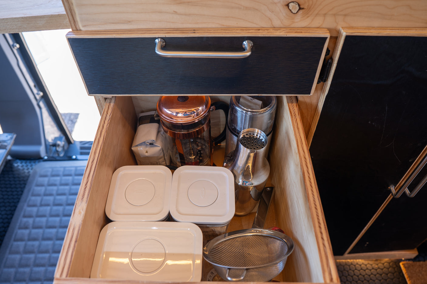 RV rental kitchen drawer: Organized storage with a French press, grinder, containers & strainer for compact living.