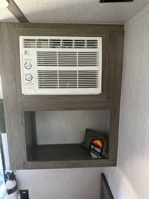 RV rental interior featuring a built-in air conditioner & storage shelf. Enhances comfort on the road.