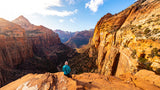 A person views a majestic, colorful canyon. Your RV rental adventure awaits at stunning national parks like Zion!