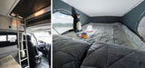 RV rental interior: Ladder leads to a cozy sleeping loft with quilted bed, lamp, plush bear, and a scenic lake view.