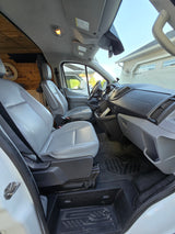 Spacious front cabin of an RV rental camper van, featuring grey seats, dashboard, and custom wood paneling.