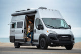 Man in a modern silver NOOVO camper van parked by the ocean. Discover the perfect rv rental for scenic road trips.