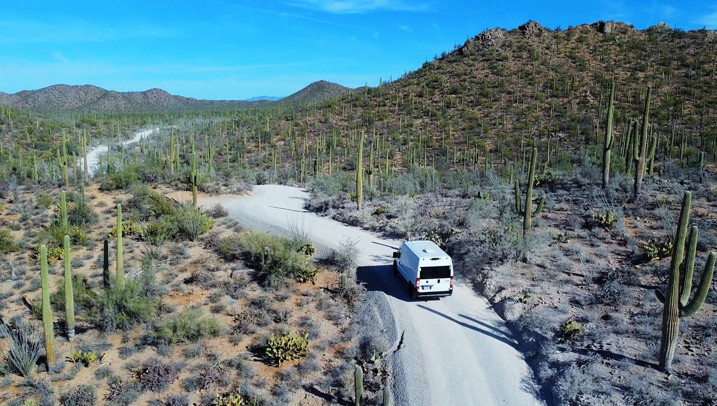 A white RV rental van winds through a stunning desert landscape filled with saguaro cacti. — photo 20