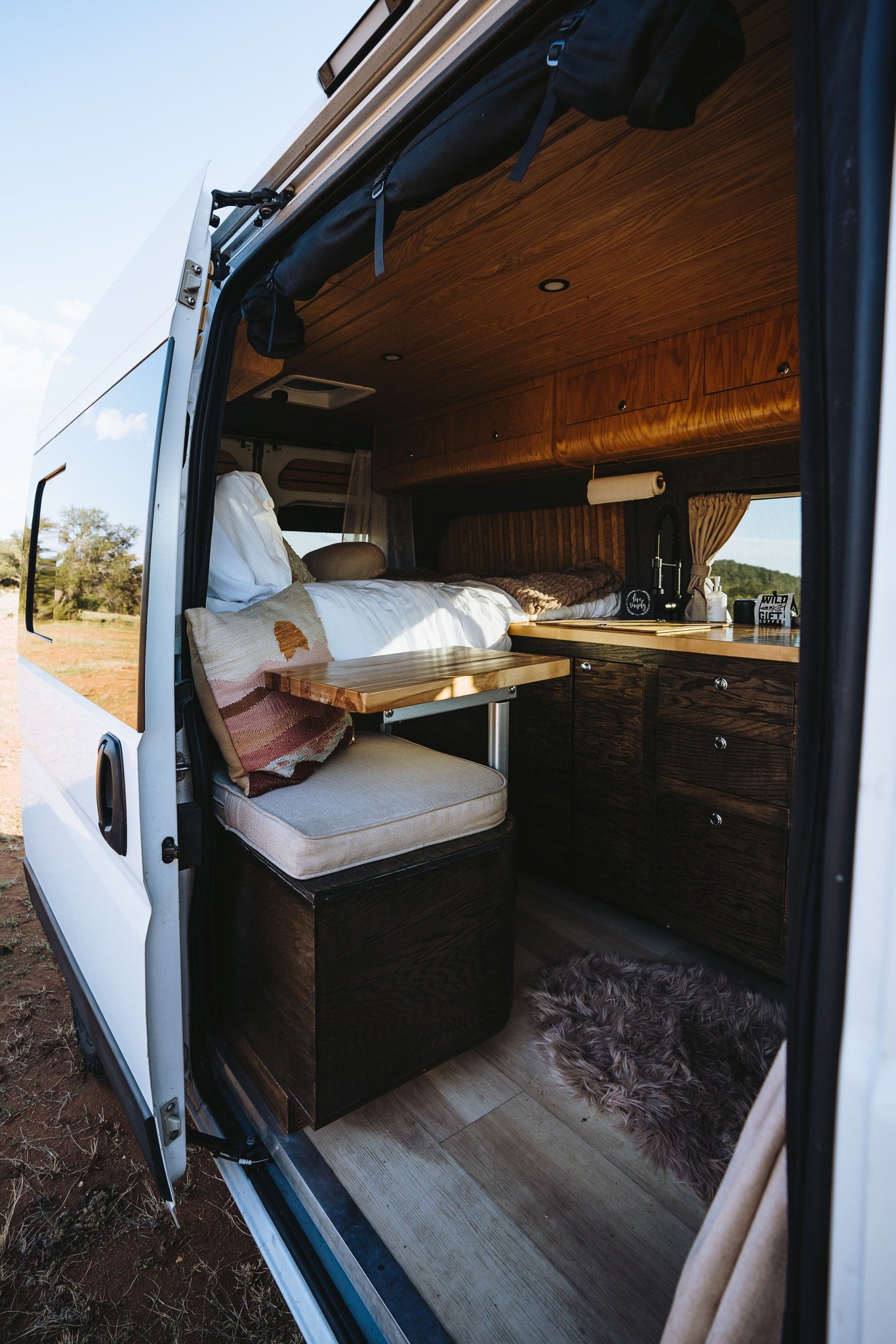 Cozy camper van interior, perfect for your next RV rental! Features a comfortable bed, dining table, and kitchen for travel. — photo 2