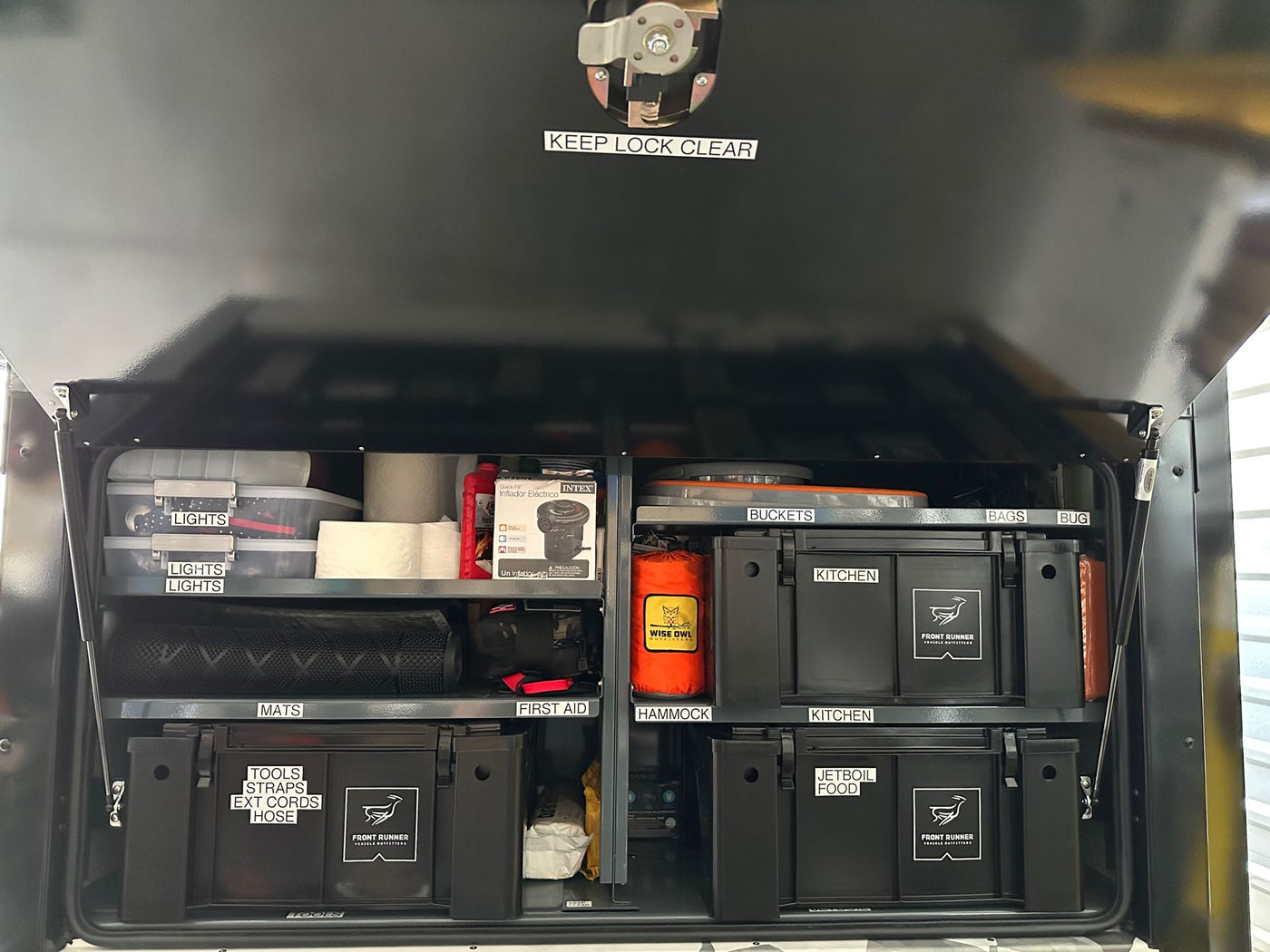 Inside an organized **rv rental**, a custom storage system with labeled bins for camping essentials: kitchen, tools, lights, and more. — photo 4