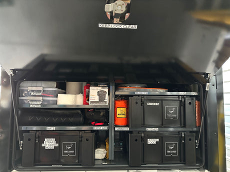 Inside an organized **rv rental**, a custom storage system with labeled bins for camping essentials: kitchen, tools, lights, and more.