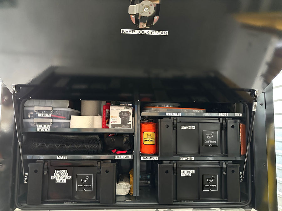 Inside an organized **rv rental**, a custom storage system with labeled bins for camping essentials: kitchen, tools, lights, and more.