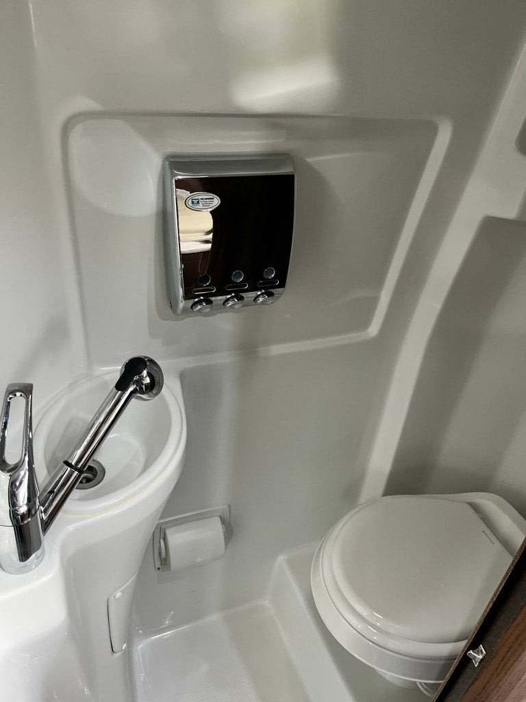  and sleek wood-look flooring.|Compact RV rental wet bath: white molded unit with sink — photo 8