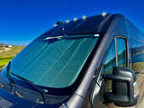 This dark grey RV rental van with a sunshade is ready for scenic road trips, parked for lakeside camping.