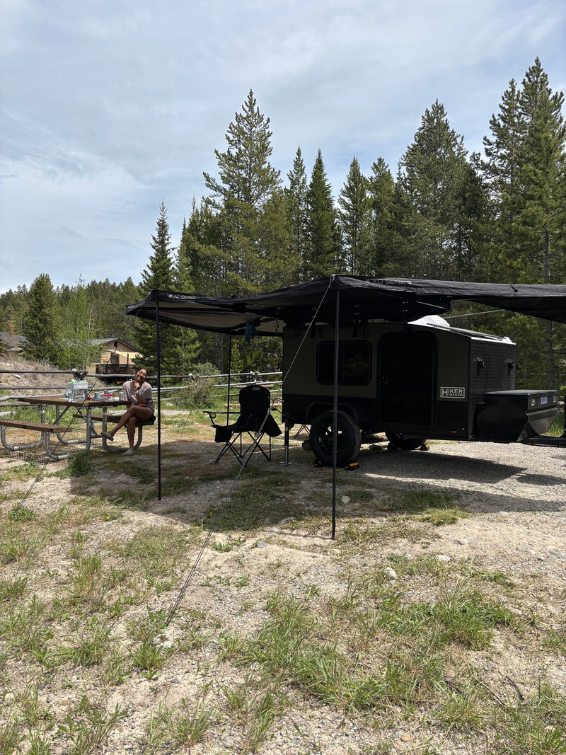  ready for adventure under an overcast sky.|Enjoying nature with an **rv rental**! A woman relaxes by her Hiker Trailer camper — photo 2