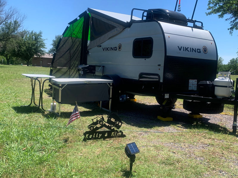 A light-colored Viking RV rental is set up for outdoor living, featuring an awning, grill, and prep table, under a clear sky. — photo 6