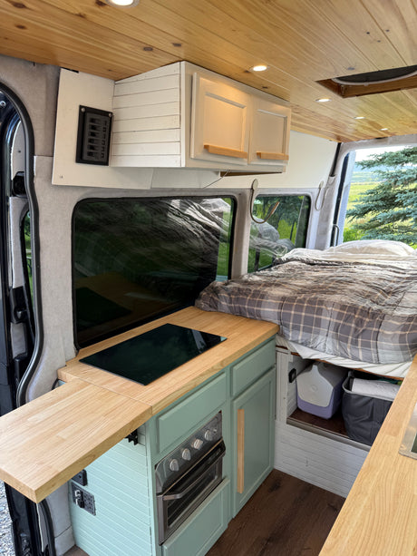 Explore this RV rental's clever interior: a compact kitchen, comfy bed, and scenic views from the window.