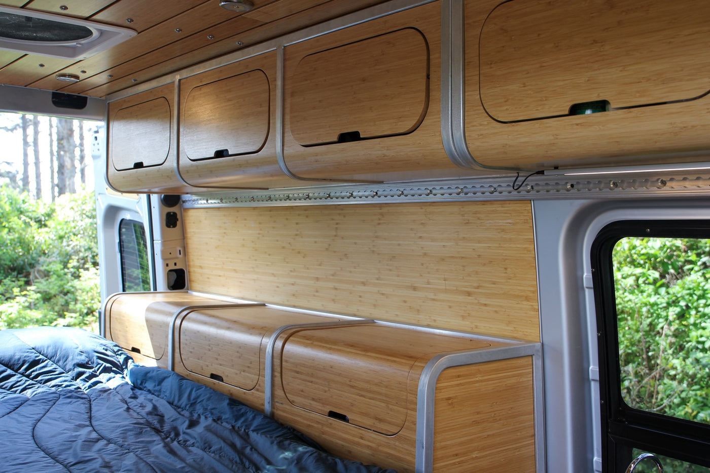 An RV rental interior with sleek bamboo cabinets, bed, and wall panels, offering a cozy mobile living space. — photo 6