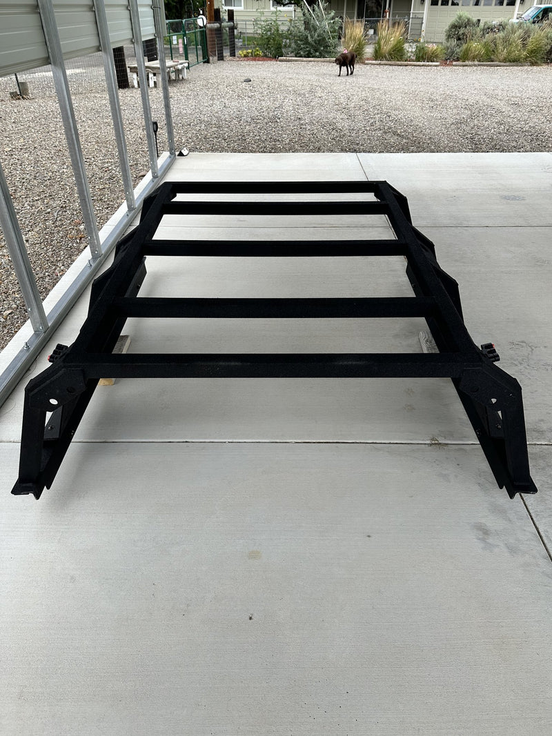 Full-length view of the bed rack from the tailgate end showing all five 2 inch square tube crossbars, the quarter inch L angle running the length of the bed and the four bed mounting feet — photo 2