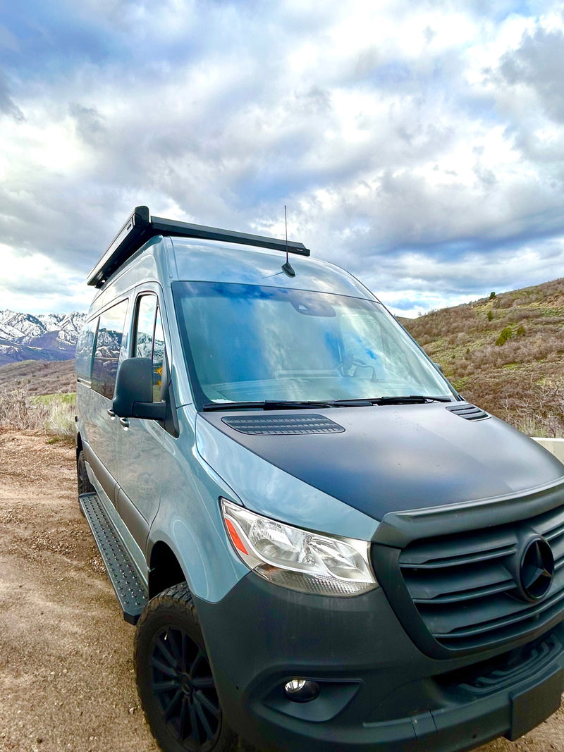 This customized Mercedes Sprinter van, perfect for an RV rental, is parked on a dirt road amidst scenic mountains under a cloudy sky. — photo 7