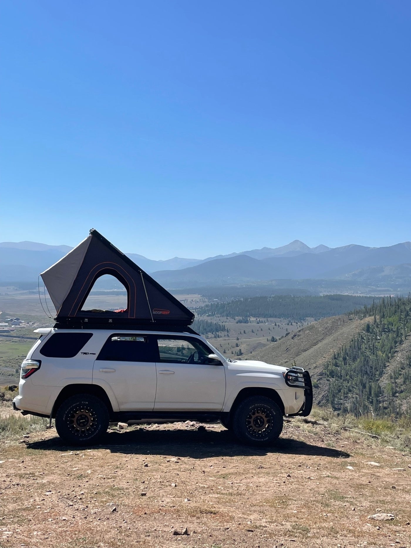 Experience mountain camping! White 4Runner with a rooftop tent deployed, ideal for an RV rental journey overlooking a valley. — photo 12