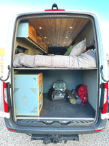 Experience an RV rental! This camper van's rear reveals a raised bed, cozy lighting, and spacious under-bed storage for your gear.