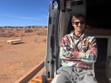 Man relaxing in an RV rental van, taking in the stunning desert landscape. Perfect for a road trip adventure.