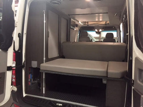 Explore this RV rental's comfortable and modular camper van interior. Features include a convertible bed & storage.