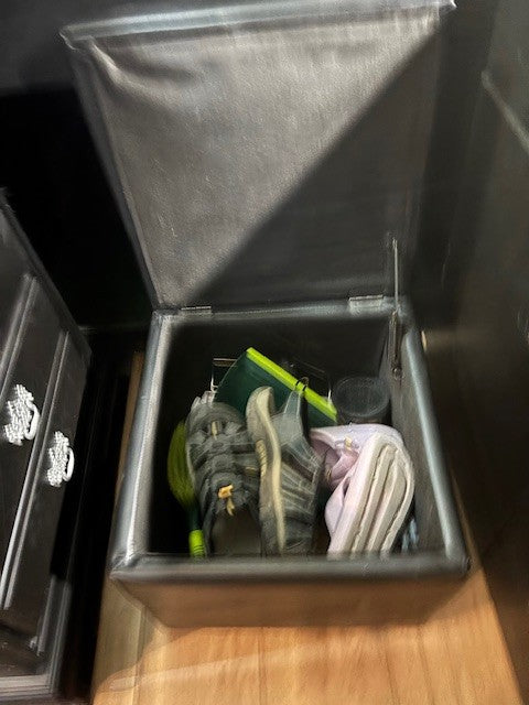 Open storage ottoman in an RV rental, revealing shoes, sandals, and essentials. Ideal for compact organization.