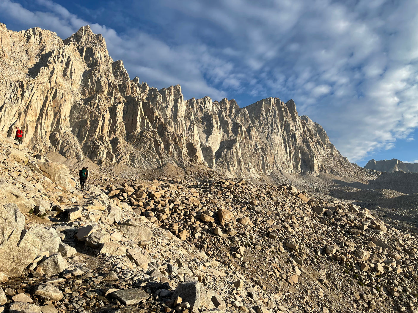 Majestic mountain range, rugged terrain, and hikers on a rocky trail. Ideal for an outdoor adventure accessible via RV rental.