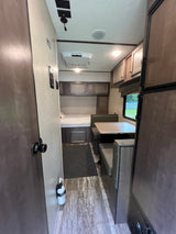 This RV rental interior showcases a cozy bedroom, versatile dinette, and compact kitchen area. Note the on-board amenities.