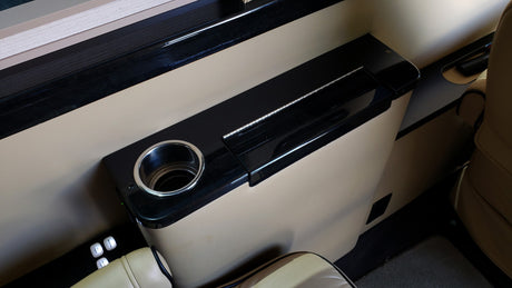 Inside an RV rental: a plush interior featuring a built-in console with cup holder and lighting controls for passenger comfort.