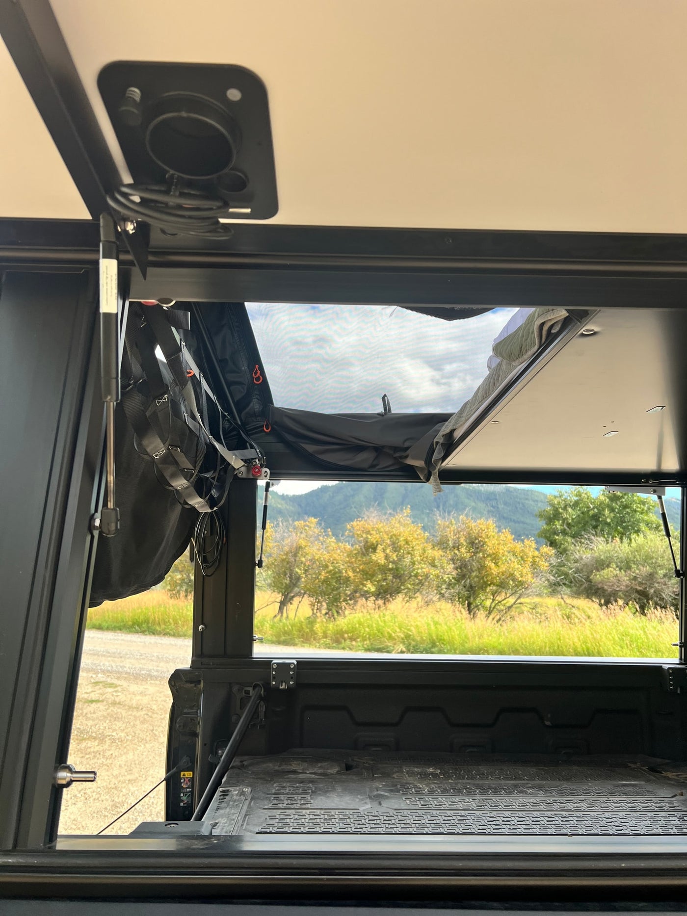Relax inside this RV rental truck bed camper. An open pop-top and mesh window offer serene views of mountains and nature. — photo 18