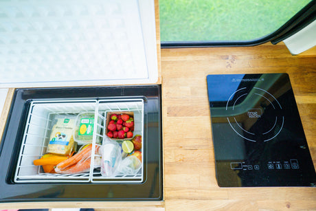RV rental kitchen: open fridge with fresh groceries & a True Induction cooktop on the wood counter.