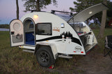 Compact T@G Boondock RV rental with open side door and rear kitchen hatch, ready for camping in the outdoors at dusk.